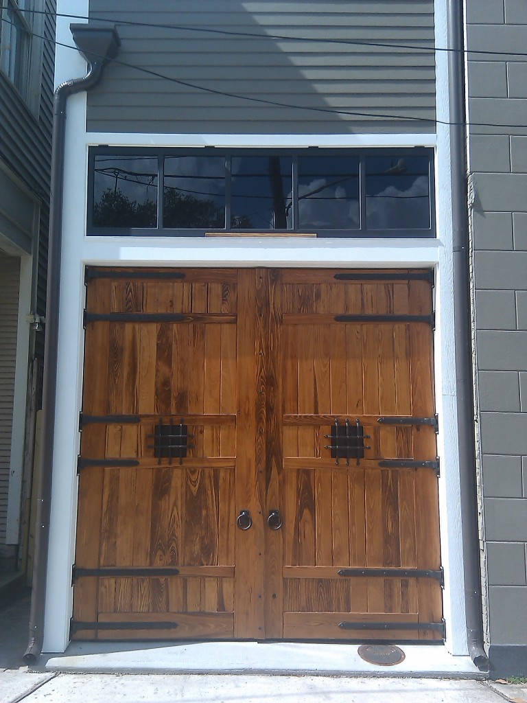 New Orleans historic carriage house doors with dark bronze hardware adorning it, custom wood doors
